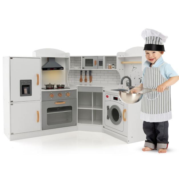 White corner play kitchen with a child wearing the included-style chef outfit