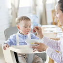 Supervised feeding in the grey high chair with shoulder harness fastened
