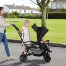 Black sit and stand double stroller, side view of seated and standing travel positions