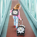 Child wearing the black penguin backpack and pulling the matching suitcase, with the photographed pillow and tag.