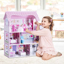 Child arranging miniature furniture inside the pink wooden dollhouse