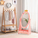 Pink freestanding dressing mirror with an empty lower shelf beside a clothing rack.