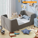 Grey velvet upholstered toddler bed frame with shaped side panels in a styled room; mattress not included