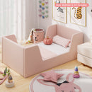 Pink velvet upholstered toddler bed frame with shaped side panels in a styled room; mattress not included