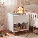 White scalloped bedside table beside a bed