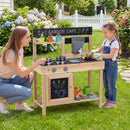 Adult supervising a child at the Natural wooden mud kitchen with example garden accessories