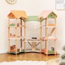 Wooden dollhouse with pink, orange and green roofs arranged in a room