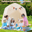 Beige dome play tent behind adults and children at an outdoor picnic; picnic items and blanket not included