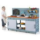 Child beside the Blue wooden mud kitchen, showing its overall size with example play accessories