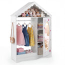 White house-shaped kids wardrobe with mirror door and hanging rail; clothing and toys are styling props