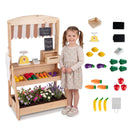 Natural wooden market stand beside a child with the supplied toy produce, chalkboards, toy scale, pretend card reader and paper bag shown separately