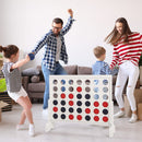 Family gathered around the White wooden four-in-a-row game indoors