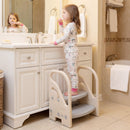Child standing on the beige and grey step stool while brushing their teeth at a bathroom basin