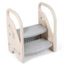 Beige and grey toddler step stool viewed from the front left, showing two grooved steps and side fasteners